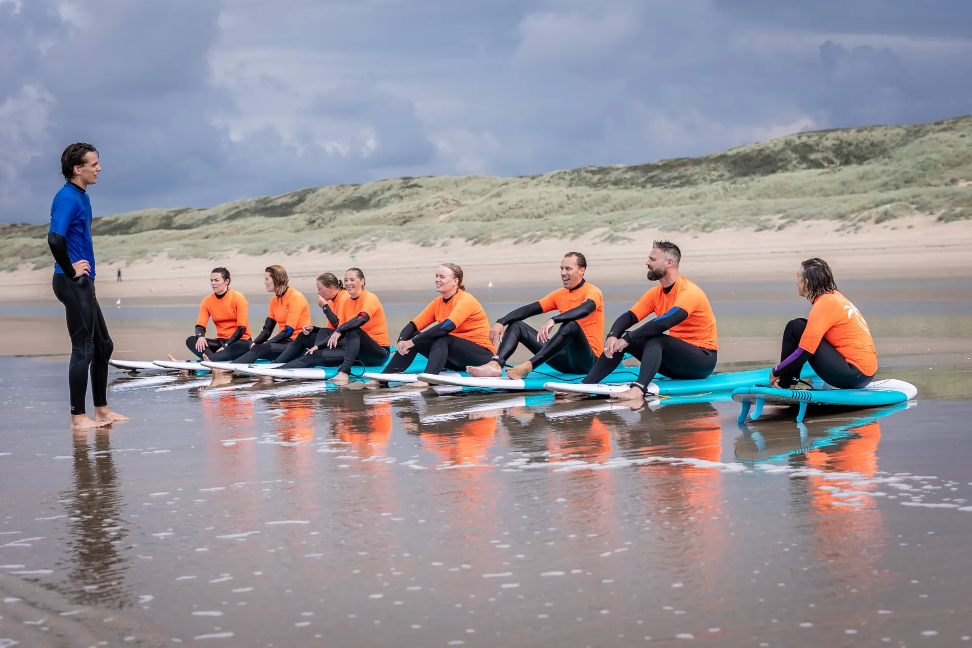 De groep luistert naar de surfinstructeur terwijl ze op hun planken zitten