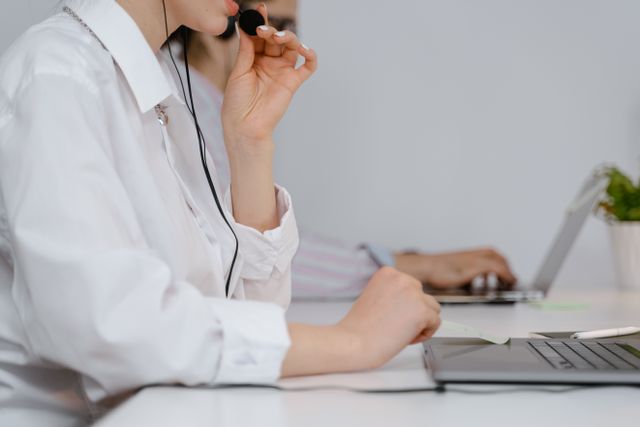 Supportmedewerker met headset achter een laptop