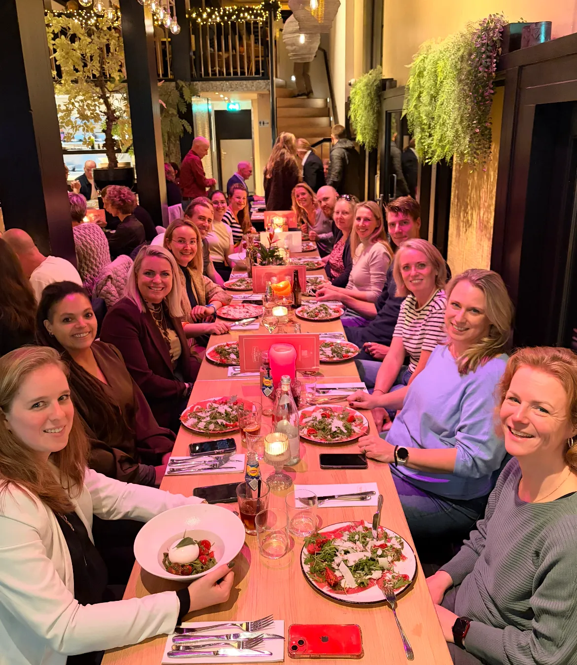 De groep zit samen aan een lange tafel