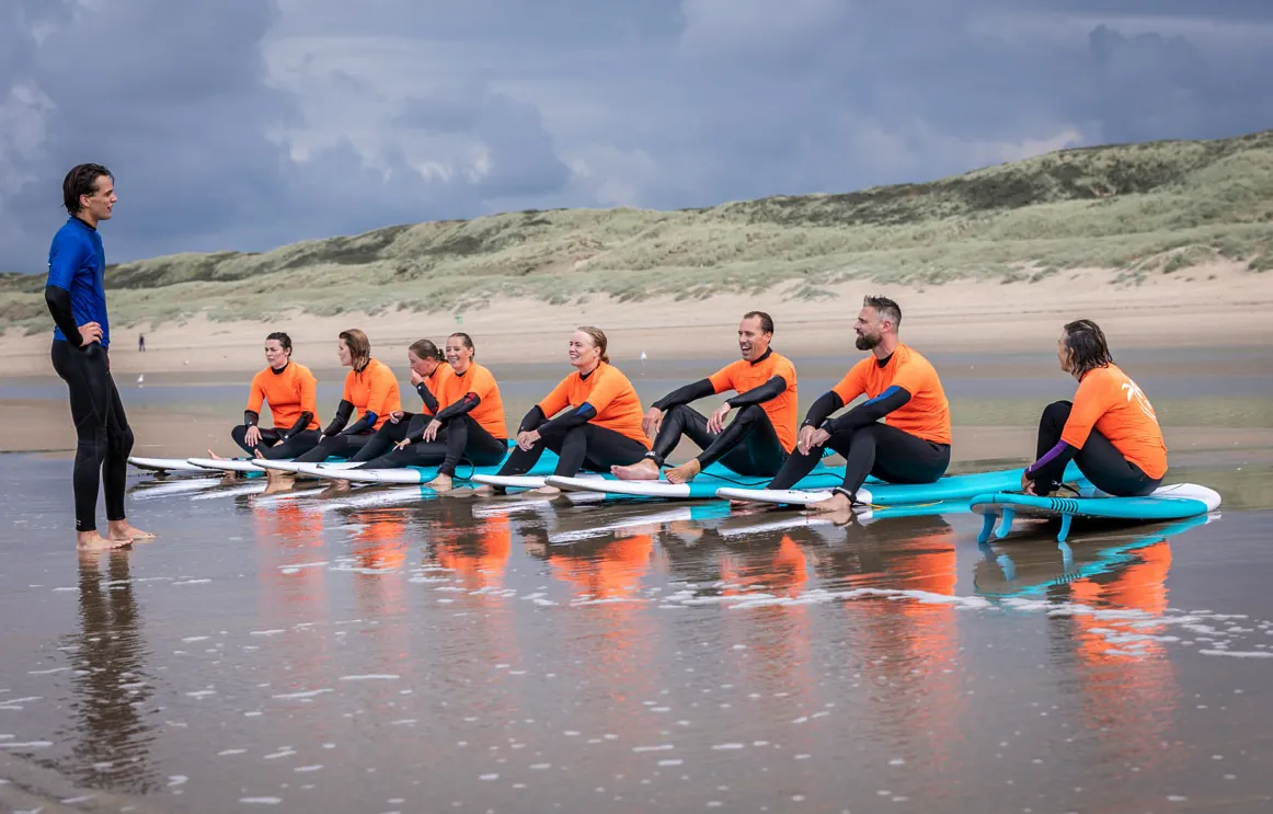 Het team krijgt surfles op het strand van Bloemendaal