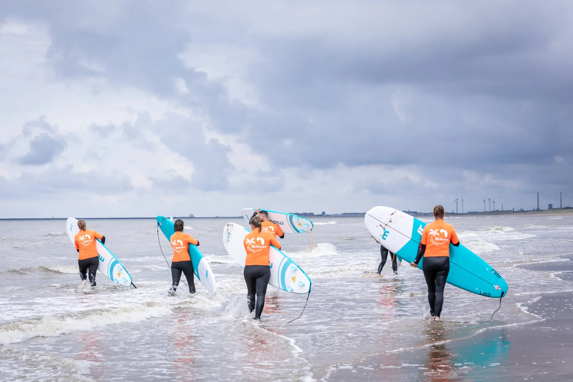 Partners dragen hun surfplanken de zee in